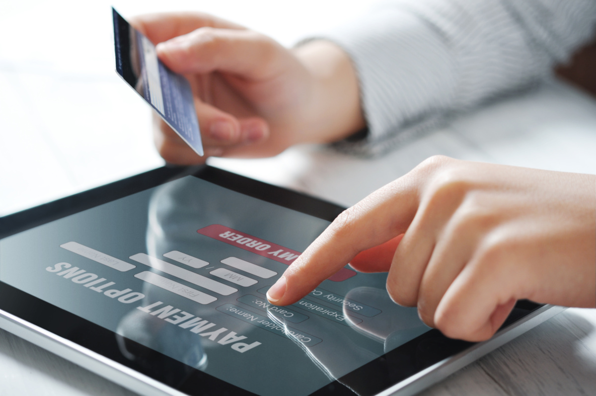A person holding a credit card while making an online transaction on a tablet